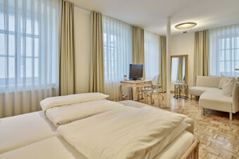 Bright hotel room at Lodner&acute;s Genie&szlig;erhotel & Hotel Drei Mohren with a double bed, sheer curtains, desk, chair, sofa, and mirror