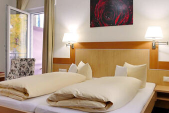 Luminosa e accogliente camera dell'Hotel Garni Metzingen con due letti singoli, lampade da comodino e balcone con vista sul verde.