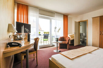 Camera modernamente arredata con balcone e area salotto nell'Hotel Garni Metzingen, luminosa e confortevole per gli ospiti.