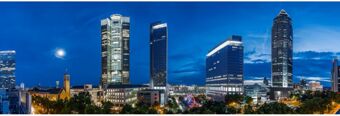 Nighttime cityscape of Frankfurt with illuminated skyscrapers and the moon in the sky including NH Hotel Frankfurt Messe buildings