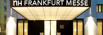 Entrance of NH Hotel Frankfurt Messe with illuminated signage and large glass doors in a modern building facade