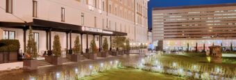Night view of the outdoor seating area and entrance of NH Collection Roma Palazzo Cinquecento with illuminated garden and modern building background