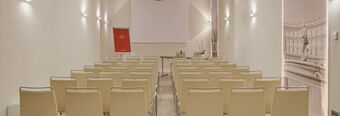 Conference room setup with beige chairs, a table with bottles and a flipchart at NH Collection Roma Palazzo Cinquecento