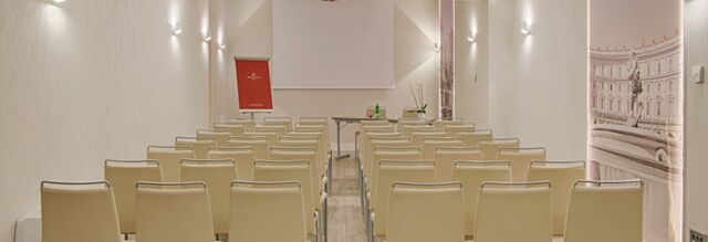 Conference room setup with beige chairs, a table with bottles and a flipchart at NH Collection Roma Palazzo Cinquecento