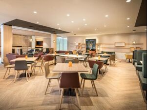 Hell eingerichteter Restaurantbereich mit modernen Tischen und St&uuml;hlen im Holiday Inn Mannheim City - Hauptbahnhof, gem&uuml;tlich und einladend gestaltet.