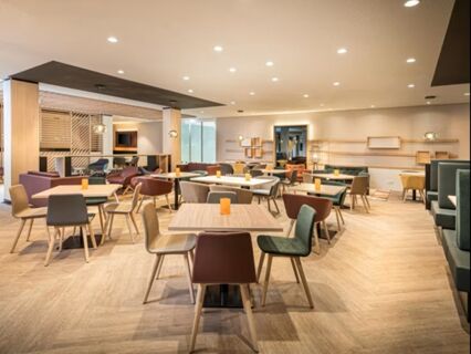 Hell eingerichteter Restaurantbereich mit modernen Tischen und St&uuml;hlen im Holiday Inn Mannheim City - Hauptbahnhof, gem&uuml;tlich und einladend gestaltet.