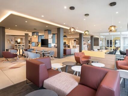 Moderne Lounge mit bequemen Sesseln und Tischen in der Lobby des Holiday Inn Mannheim City - Hauptbahnhof, hell und einladend gestaltet.