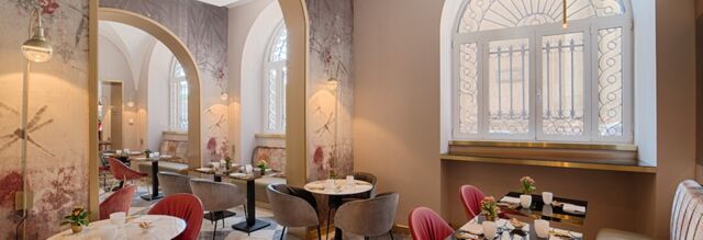 Dining area at Hotel NH Collection Roma Fori Imperiali with marble tables, red and gray chairs, and arched windows with iron grilles