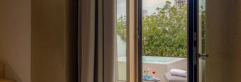 Balcony with outdoor bathtub, small table with drinks, and gray seating at NH Collection Milano CityLife hotel room
