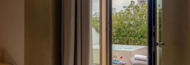 Balcony with outdoor bathtub, small table with drinks, and gray seating at NH Collection Milano CityLife hotel room