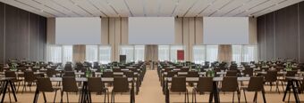 Large conference room at NH Collection Milano CityLife with rows of tables and chairs and water bottles on each table