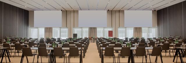 Large conference room at NH Collection Milano CityLife with rows of tables and chairs and water bottles on each table