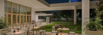 Outdoor seating area with tables, chairs, plants, and ambient lighting at night at NH Collection Milano CityLife