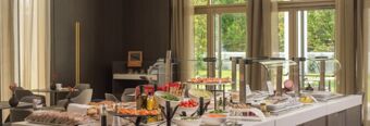 Buffet setup with breads, vegetables, and cold cuts displayed in a bright dining area at NH Collection Milano CityLife