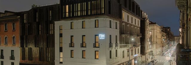 Hotel NH Milano Corso Buenos Aires building illuminated at dusk with surrounding architecture and street full of cars and lights