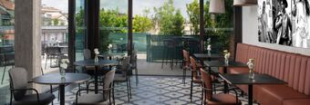 Indoor dining area with tables and chairs facing glass doors leading to an outdoor terrace at Hotel NH Milano Corso Buenos Aires