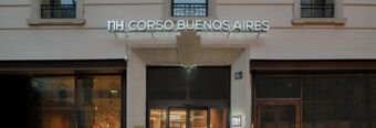 Entrance of Hotel NH Milano Corso Buenos Aires with illuminated sign above glass double doors and large windows on both sides