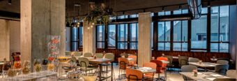 Spacious dining area with large windows, modern chairs and tables, and food display at Hotel NH Milano Corso Buenos Aires