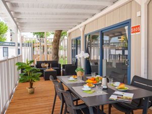 Outdoor covered terrace at Rimini Family Resort with a dining table set for breakfast and black wicker seating area nearby