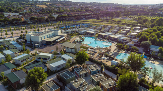 Aerial view of Romagna Family Resort showing swimming pools, sun loungers, umbrellas, cabins, and trees surrounding the area