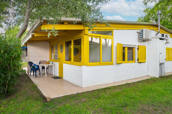 White and yellow bungalow with patio furniture and greenery surrounding the property at Adriano Family Collection