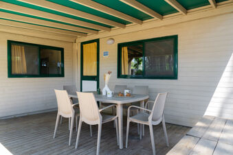 Outdoor patio area with beige wicker chairs around a table set with pastries and cups at Adriano Family Collection