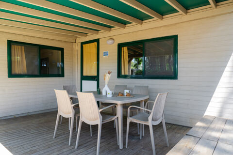 Outdoor patio area with beige wicker chairs around a table set with pastries and cups at Adriano Family Collection