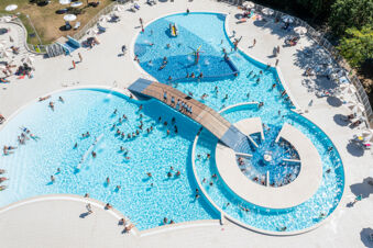 Multiple swimming pools with people swimming and lounging under umbrellas at Adriano Family Collection resort