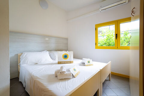 Bedroom with two single beds pushed together, white bedding and yellow window frame at Adriano Family Collection
