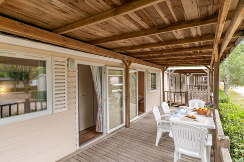 Wooden patio with white plastic chairs and table set with breakfast items outside rooms at Marina Family Resort