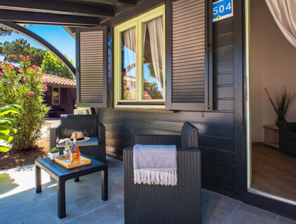 Outdoor seating area with wicker chairs, a small table with a bottle and glasses, outside room 504 at Milano Marittima Boutique Resort