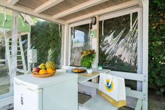 White wooden covered outdoor dining area with fruit basket, flowers, croissants, and a bag at Adriatico Cervia Easy Camping Village
