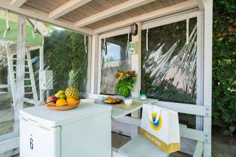 White wooden covered outdoor dining area with fruit basket, flowers, croissants, and a bag at Adriatico Cervia Easy Camping Village