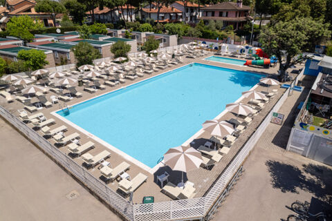 Large rectangular swimming pool with umbrellas and lounge chairs surrounded by mobile homes at Adriatico Cervia Easy Camping Village