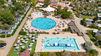 Aerial view of crowded outdoor pools with umbrellas, sunbeds, and mobile homes at Vigna sul Mar Family Collection