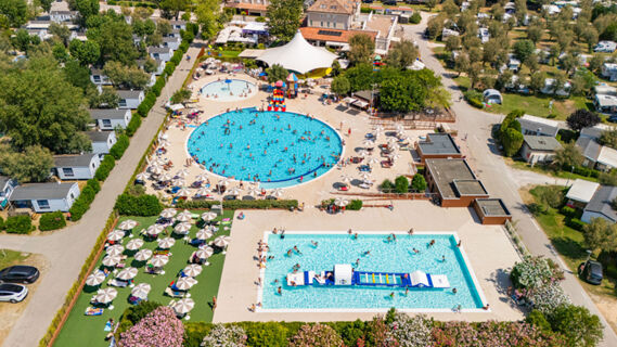 Aerial view of crowded outdoor pools with umbrellas, sunbeds, and mobile homes at Vigna sul Mar Family Collection