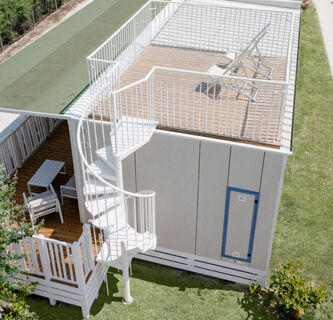 White building with wooden deck, spiral staircase, lounge chairs on rooftop, and outdoor seating area at Vigna sul Mar Family Collection