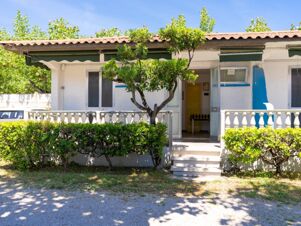 White building with tiled roof and green awnings, hedges and tree in front, entrance with open doors at Roseto degli Abruzzi Easy Camping Village