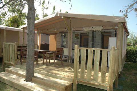 Wooden patio with table and chairs under beige awning attached to a cabin at La Risacca Family Collection outdoors