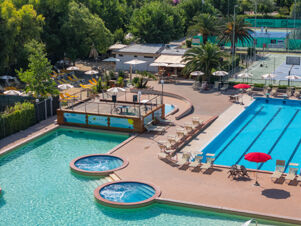 Outdoor pool area with lounge chairs, umbrellas, hot tubs, palm trees, and a tennis court at La Risacca Family Collection
