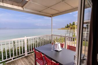 View of a covered balcony with red chairs and a table set with glasses and an ice bucket at Desenzano Boutique Resor