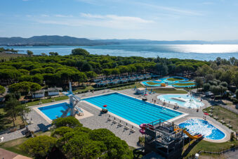 Outdoor swimming pool area with diving platforms, slides, green trees, and sea in the background at Marina Julia Family Collection