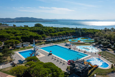 Outdoor swimming pool area with diving platforms, slides, green trees, and sea in the background at Marina Julia Family Collection