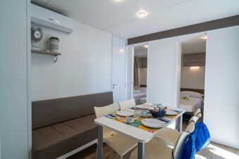 Dining table set with plates, cups, croissants, and a basket near sofa and two bedrooms at Marina Julia Family Collection