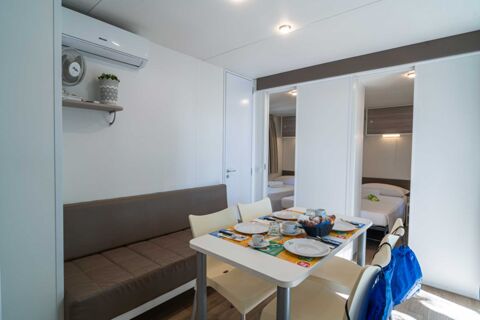 Dining table set with plates, cups, croissants, and a basket near sofa and two bedrooms at Marina Julia Family Collection