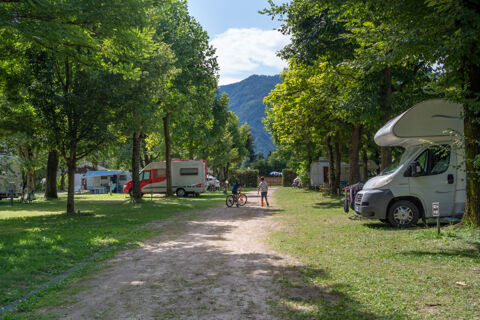 Two children playing with a ball and bicycle on a tree-lined path surrounded by camper vans at Caldonazzo Family Collection