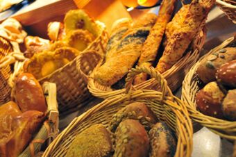 Various types of bread and baked goods displayed in wicker baskets at Akzent Hotel Stadt Schl&uuml;chtern