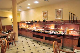 Buffet setup with various breakfast items such as bread, cold cuts, beverages, and condiments in Akzent Hotel Stadt Schl&uuml;chtern dining area