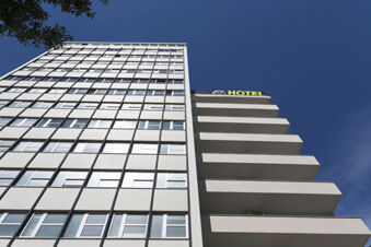 White modern high-rise building with many windows and balconies under a clear blue sky at B&B Hotel Pescara