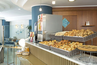 Breakfast buffet with various pastries, coffee machine, juice, and condiments on the counter at B&B Hotel Pescara
